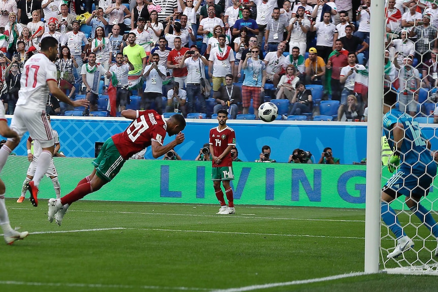 Moroccos's Aziz Bouhaddouz dives towards the ball but turns it into his own net