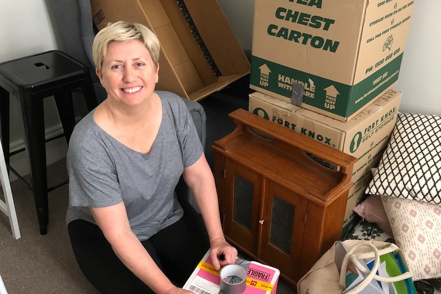 A woman sits among packing boxes