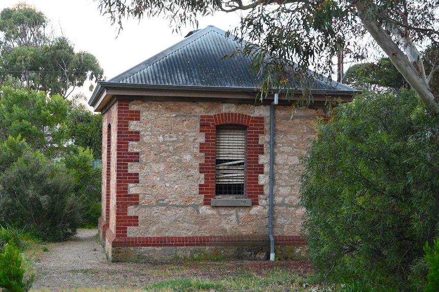 A small 1880s stone building with dilapidated wooden shutters