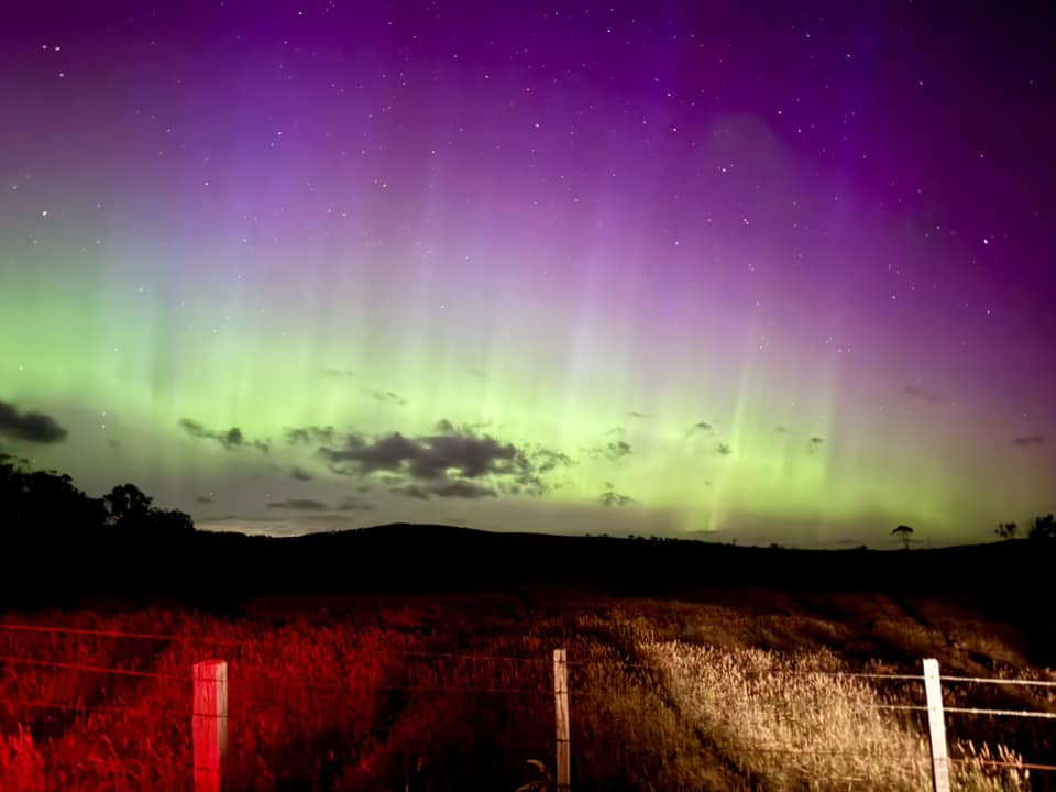 Southern lights over a field and hills