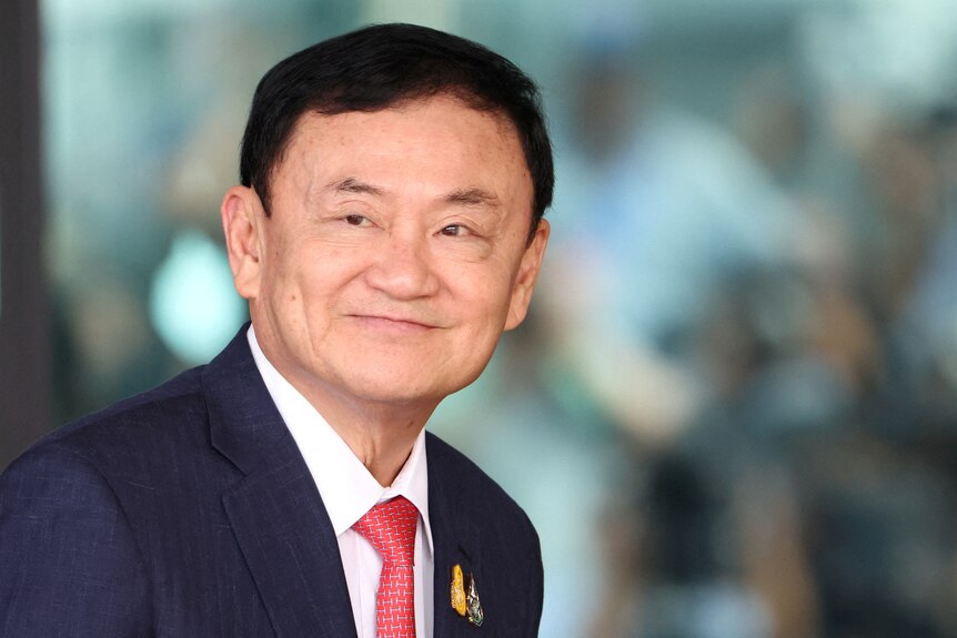 Former Thai Prime Minister Thaksin Shinawatra wearing black suit and red tie.