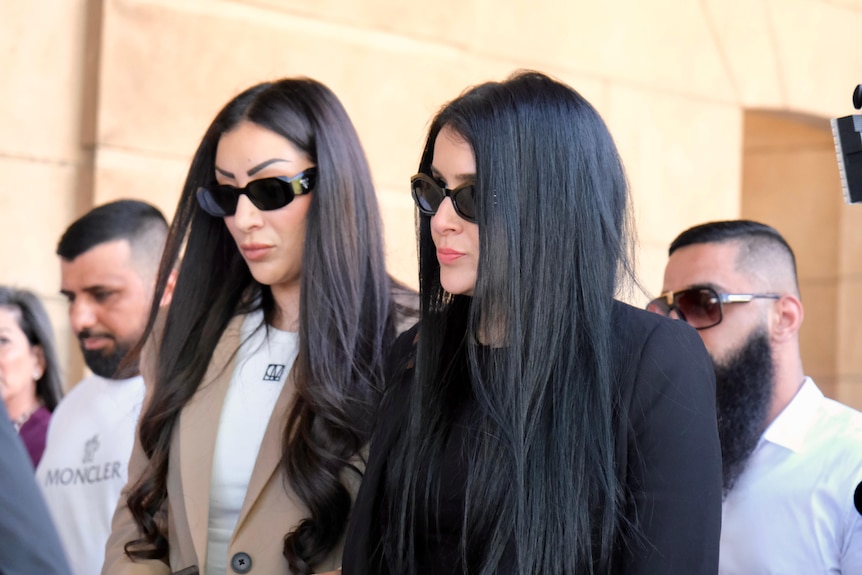Two women with long dark hair wearing sunglasses