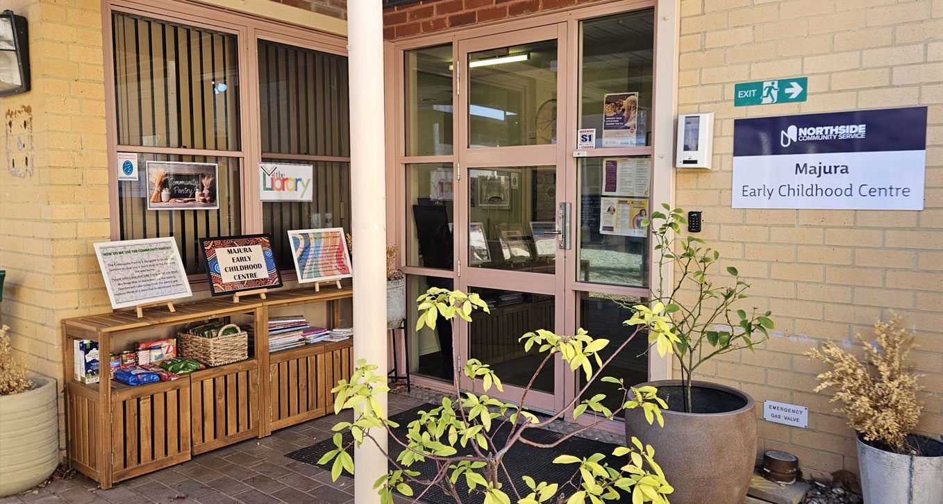 The entrance to a building with bookshelves out front and sign for the business on the wall.