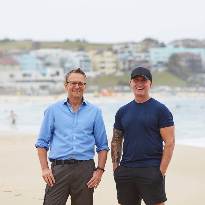 Michael Mosley and Ray Kelly stand smiling on a beach