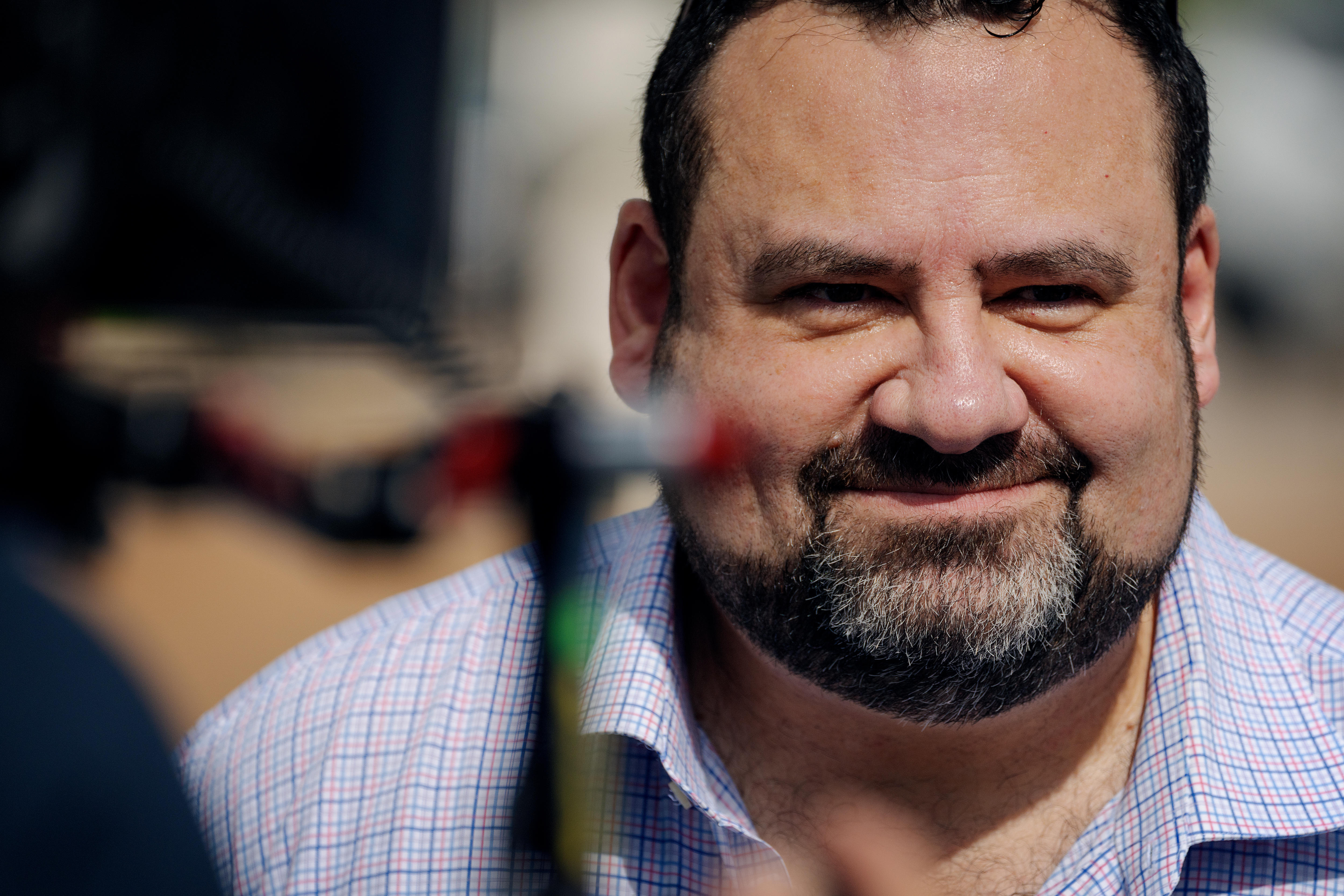 Un hombre con camisa de negocios sonríe levemente a la cámara. Es un primer plano de su rostro.