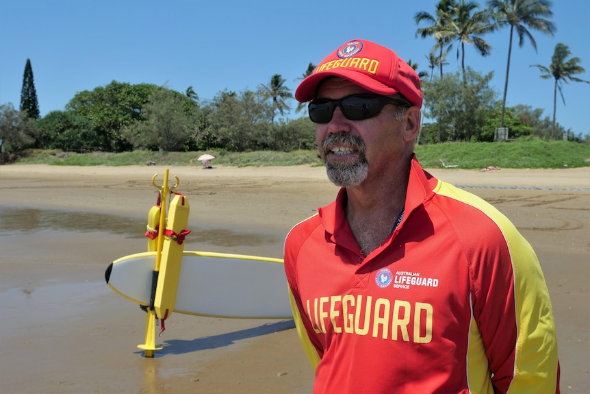 A white man in his 40s, grey goatee, wearing a lifeguard cap and long sleeve shirt, sunglasses 