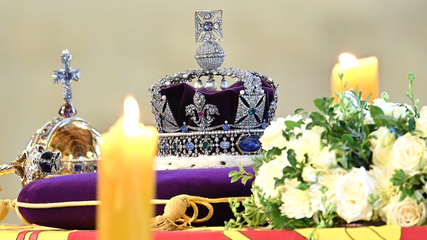 The Queen's coffin draped in the Royal Standard, with the Imperial State Crown and Sovereign's Orb and sceptre, and candles