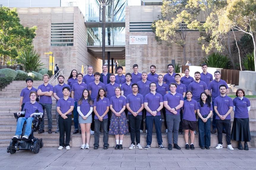 A large group of university students wearing matching shirts.