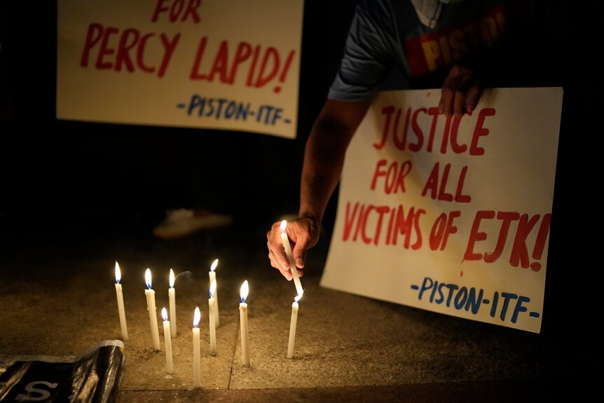 Activists hold a candle beside slogans as they condemn the killing of Filipino journalist Percival Mabasa.