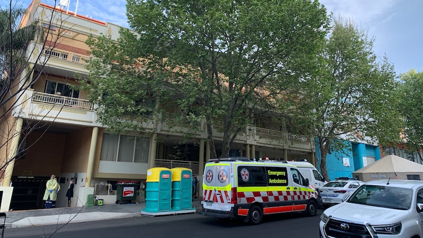 An apartment building with an ambulance and police vehicle out the front