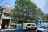 An apartment building with an ambulance and police vehicle out the front