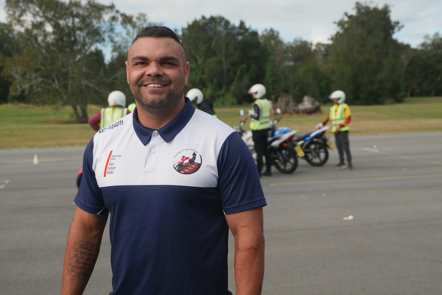 A man wearing a T-shirt helps participants at rider training