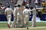 Australian players hug each other as they celebrate beating India, while Mohammed Shami looks on.