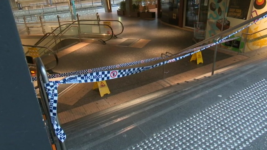 Police tape sealing off a section of a footpath and escalators