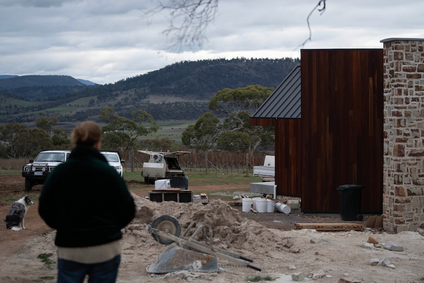 A lady looking at a building on a remote property that is being built.