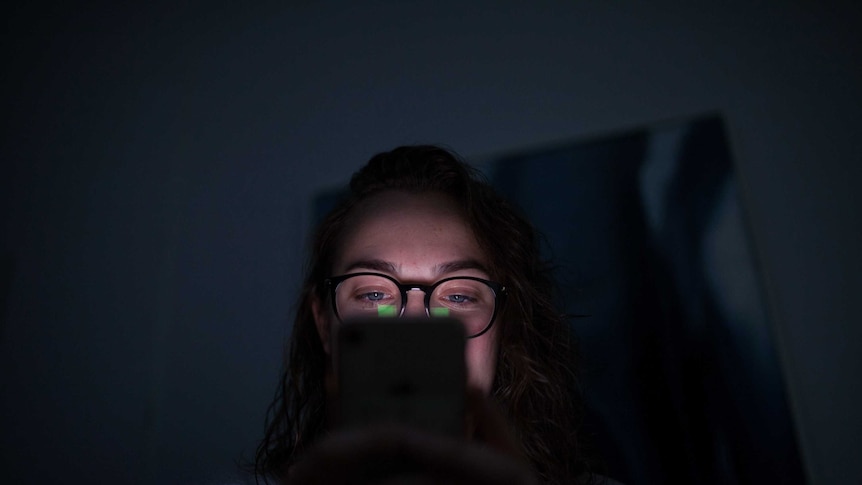 The administrator of a women's support group on Facebook looks at her iPhone in the dark.