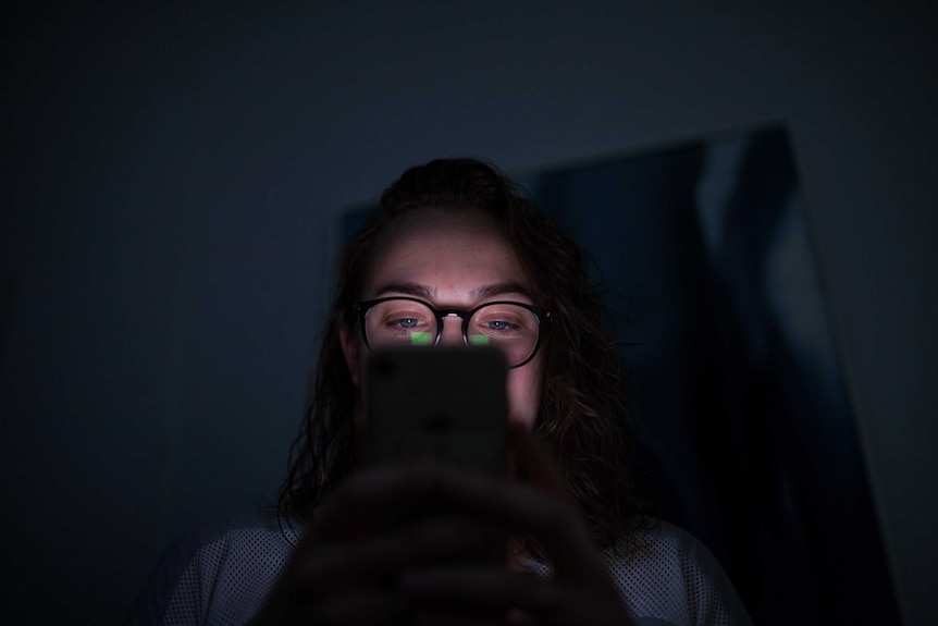 The administrator of a women's support group on Facebook looks at her iPhone in the dark.