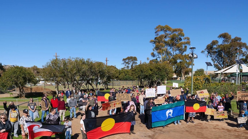 The crowd at a Black Lives Matter march in Broken Hill, with people holding flags and hand-painted signs .