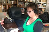 A woman sitting at a computer with headphones on. 
