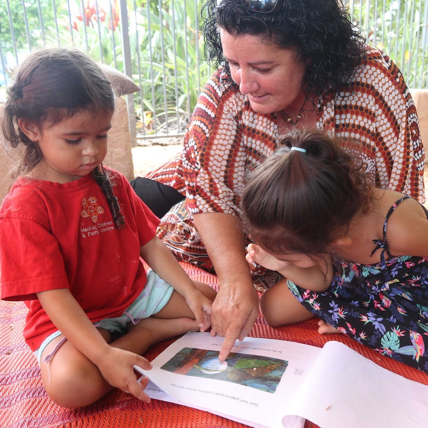 A woman reads a story to two little girls