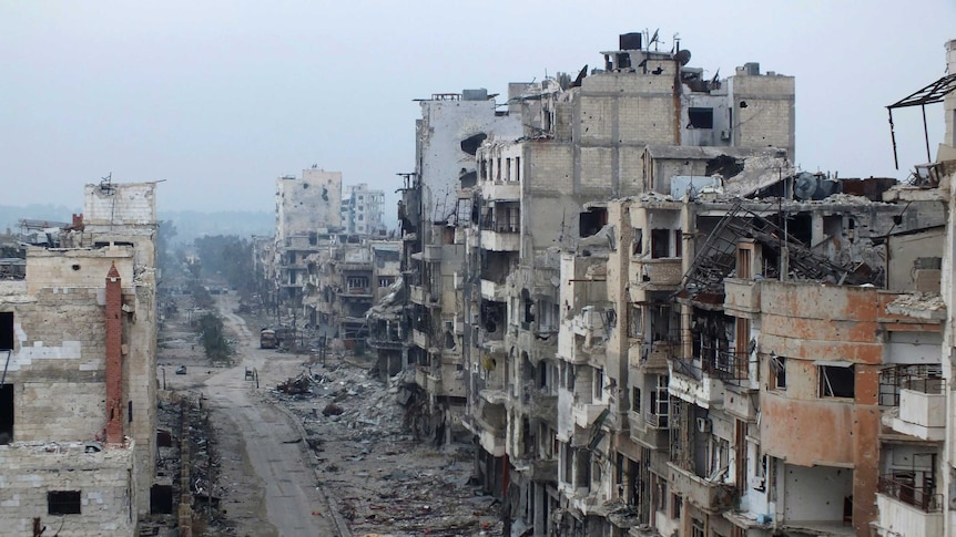 Damaged buildings line a street in the besieged area of Homs