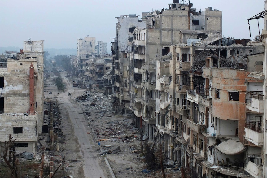 Damaged buildings line a street in the besieged area of Homs