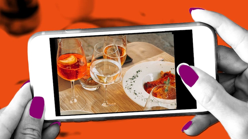 Close-up of phone showing woman taking photo of wine on a table for an article about how to travel without drinking alcohol.