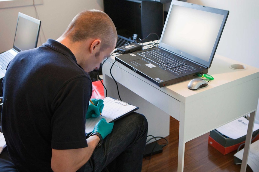 An AFP member examines a computer during Operation Thunderer.