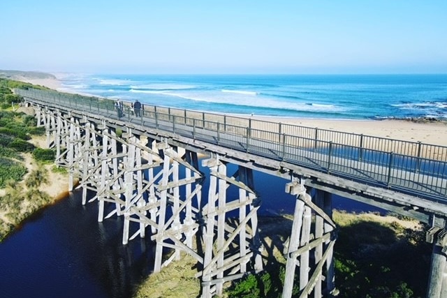 A footbridge over a waterway leading to the ocean.