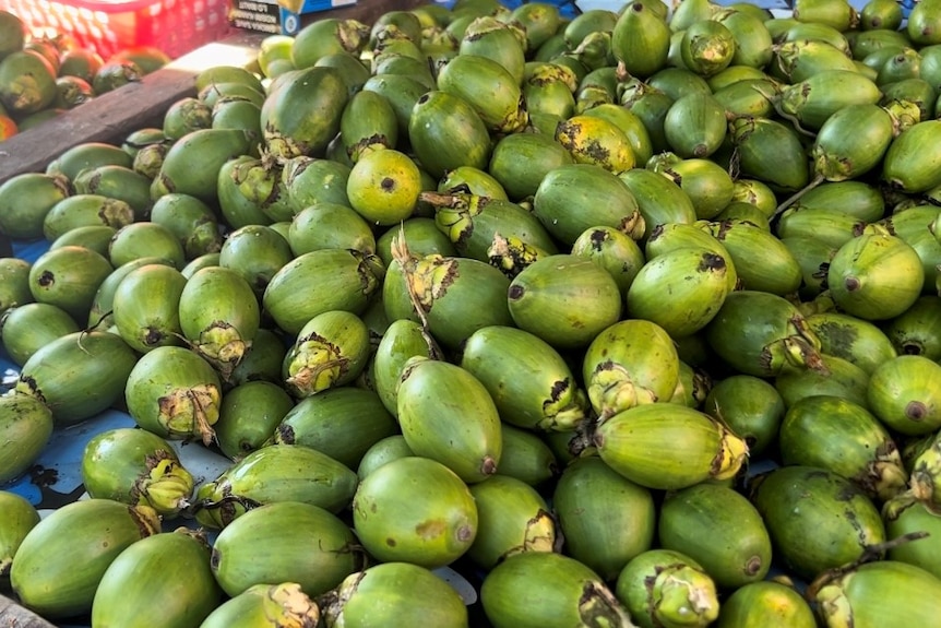 A pile of a betel nut in a market, a green lime-like fruit