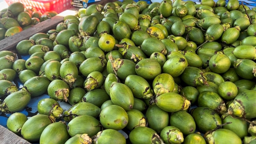 A pile of a betel nut in a market, a green lime-like fruit