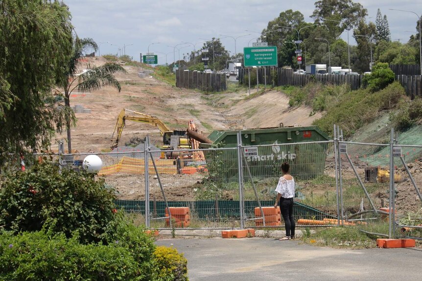 Louise Simpson standing on a laneway looking into the construction site through fencing.