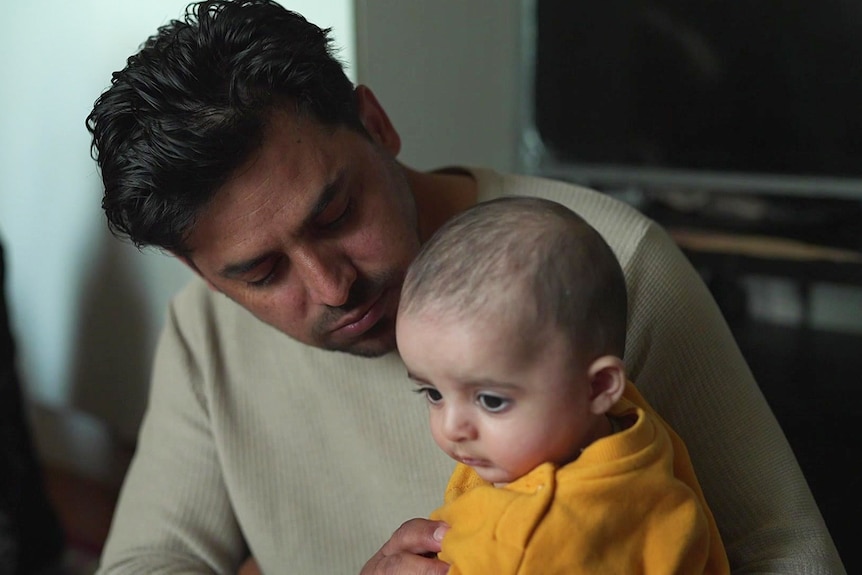 Un homme regarde son bébé.