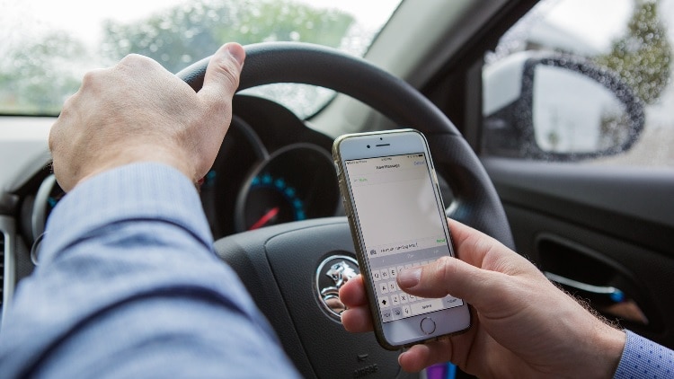 Generic image of person using phone while driving.