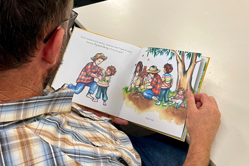A man reading a children's book.