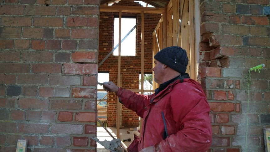 a brick layer seals some mortar or newly laid bricks on a wall