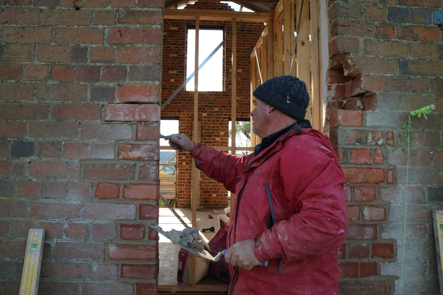 a brick layer seals some mortar or newly laid bricks on a wall