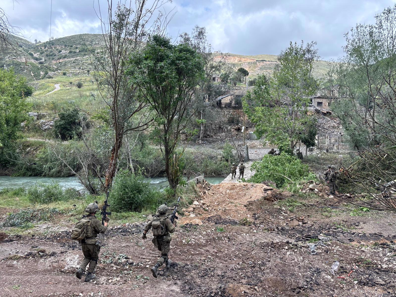 Se talan árboles, dejando tierra en un lado del río donde se encuentran los soldados, mientras que en el otro lado hay edificios de piedra que permanecen intactos.