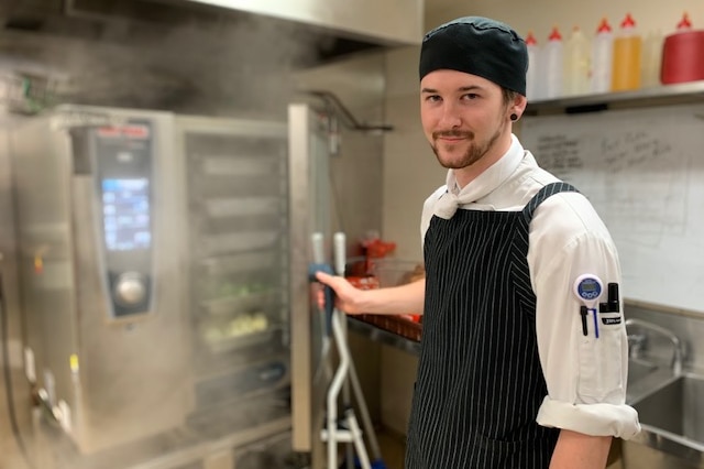 Apprentice chef Kyle Cox-McKinnon stands in a kitchen.
