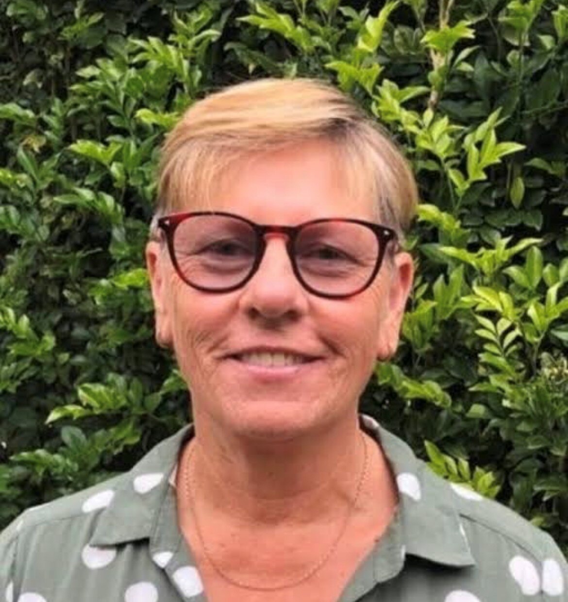 Penny wears glasses and smiles at the camera