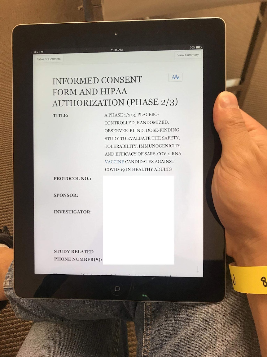 A man's hand holds an iPad which contains a consent form, headed 'Informed Consent Form'.