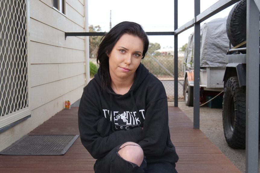 Nikita Shaw sitting on porch of a caravan park cabin at a Broken Hill caravan park.