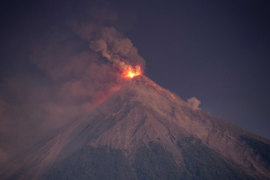 A wide, long shot shows lava and ash spilling from a volcano and rolling down the mountain.