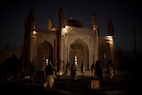 Taliban fighters walk at the entrance of a Kabul mosque at night