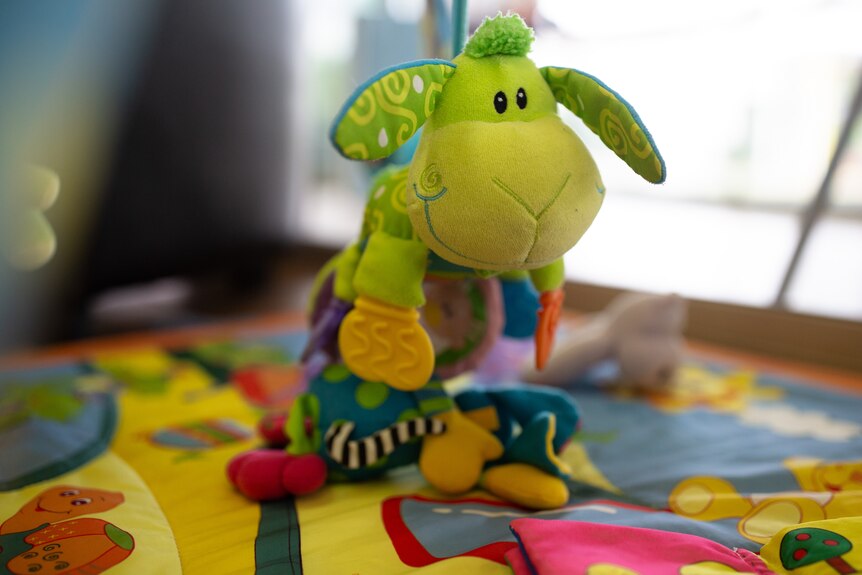 A fluffy toy standing on a colourful mat