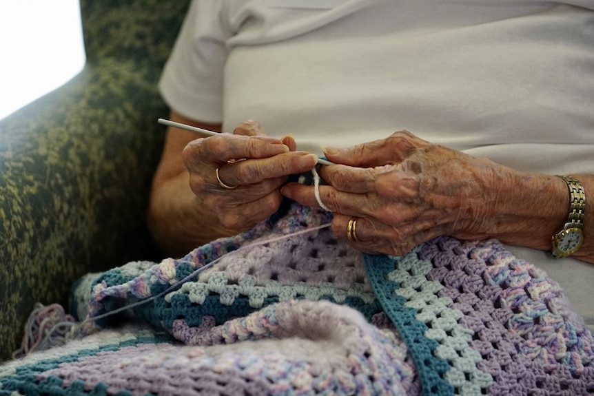 A close-up photo of an elderly woman knitting.