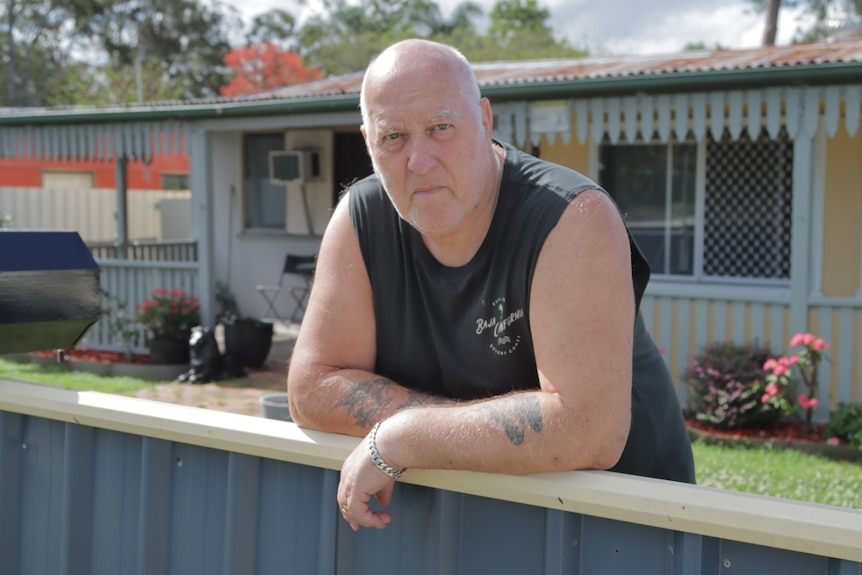 A photo of Barry McLellan leaning against his fence outside his home. 