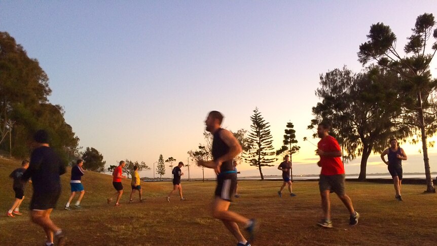 Men running in a circle by the water at Sandgate foreshore.