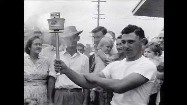 Black and white photo of man holding Olympic torch