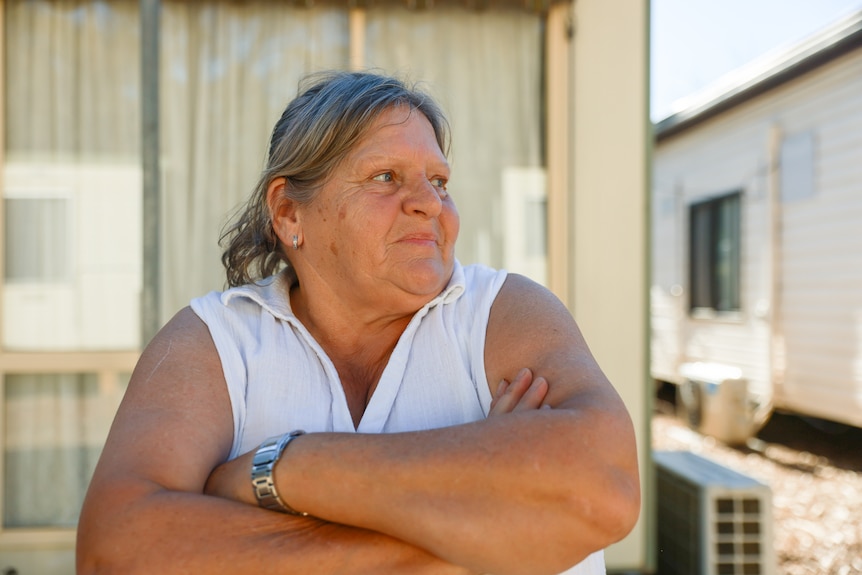A woman with her arms crossed standing outside cabins
